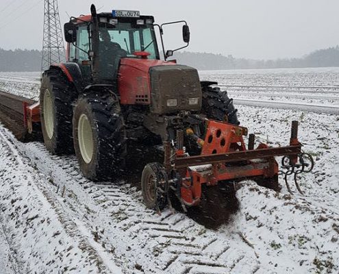 Roter Traktor formt Spargeldämme im Winter